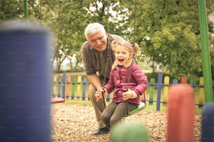 Großvater und Enkelin spielen auf dem Spielplatz.
