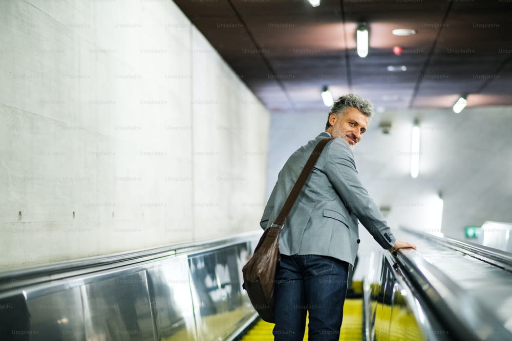 Handsome mature businessman in a city. Man on an escalator at the subway station.