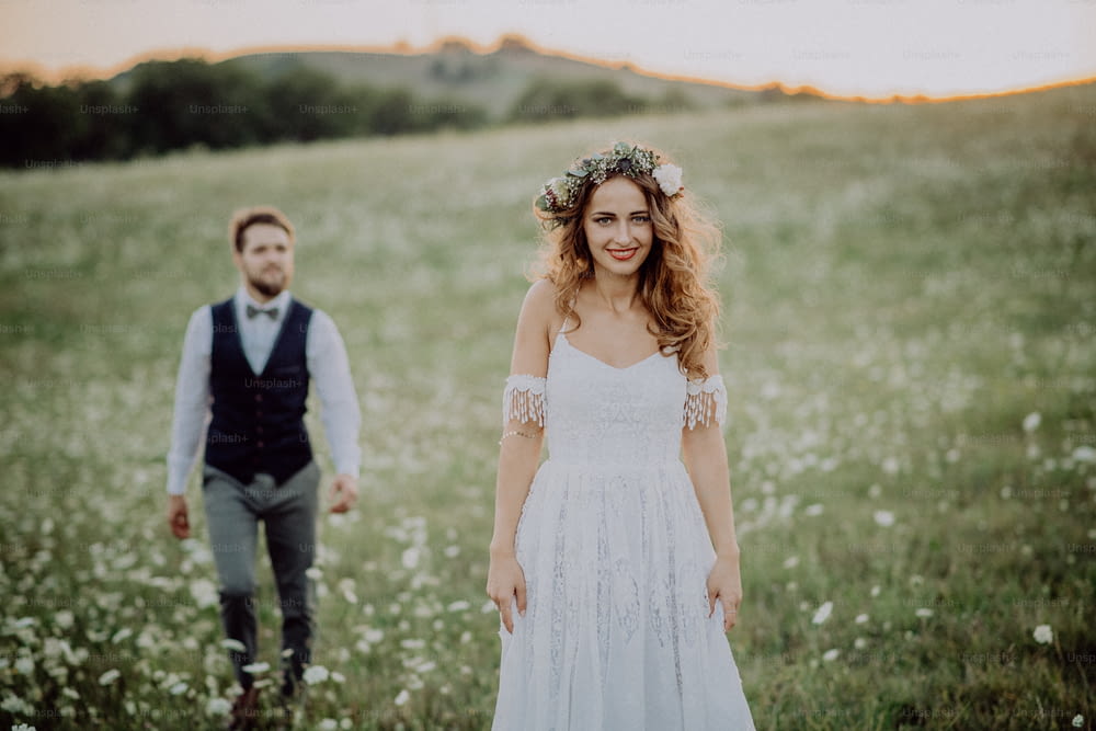 Beautiful young bride and groom outside in green nature at romantic sunset.