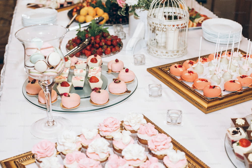 delicious candy,sweets,cupcakes,pops decorated with flowers on table at wedding reception. candy bar. tasty pink sweets for celebrations events and showers. luxury stylish catering