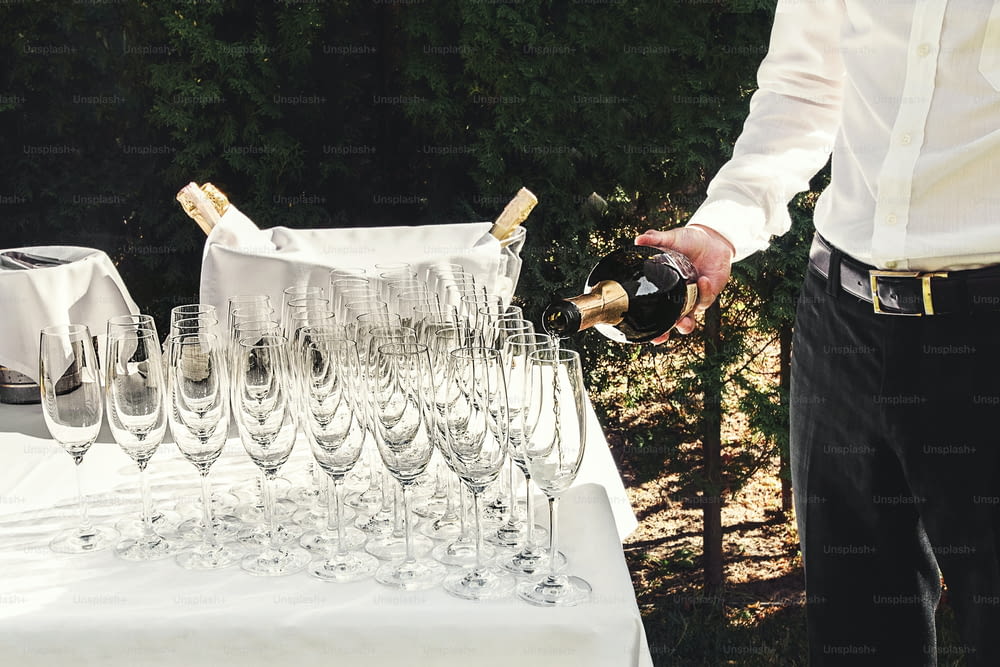 Le serveur verse des verres de luxe élégants pour le champagne sur une table pour une célébration, cathering dans le restaurant