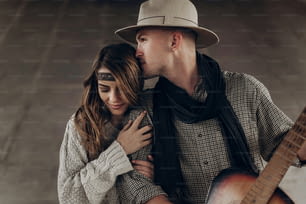 Handsome cowboy man with a guitar kissing beautiful indie woman  , while posing outdoor