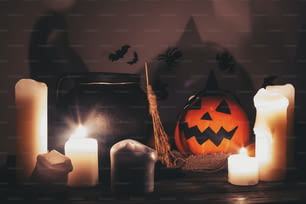 즐거운 할로윈 보내세요. 촛불, 그릇, 마녀 빗자루와 박쥐가 있는 잭 오 랜턴 호박, 어두운 으스스한 방에서 배경에 유령. 가을 할로윈 이미지입니다. 무서운 분위기의 순간