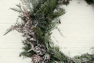 Christmas wreath. stylish rustic christmas wreath on white wooden door with pine cones,fir branches,snow. space for text. handmade decor for winter holidays.