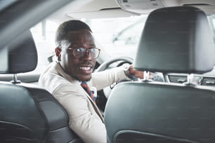 Joven hombre de negocios negro prueba de manejo de auto nuevo. Hombre afroamericano rico.