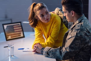Mujer joven tomada de la mano y hablando con su novio militar que está a punto de ir a la guerra.
