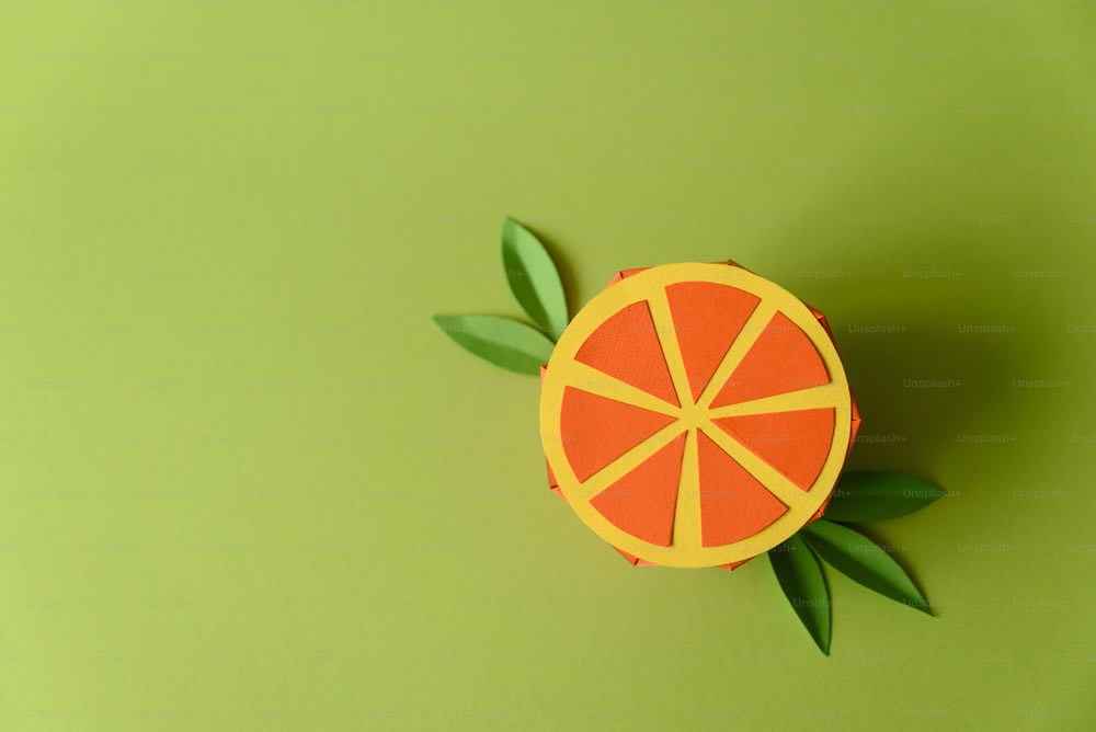 Papier orange Frucht auf grünem Hintergrund. Speicherplatz kopieren. Kreatives oder künstlerisches Food-Konzept