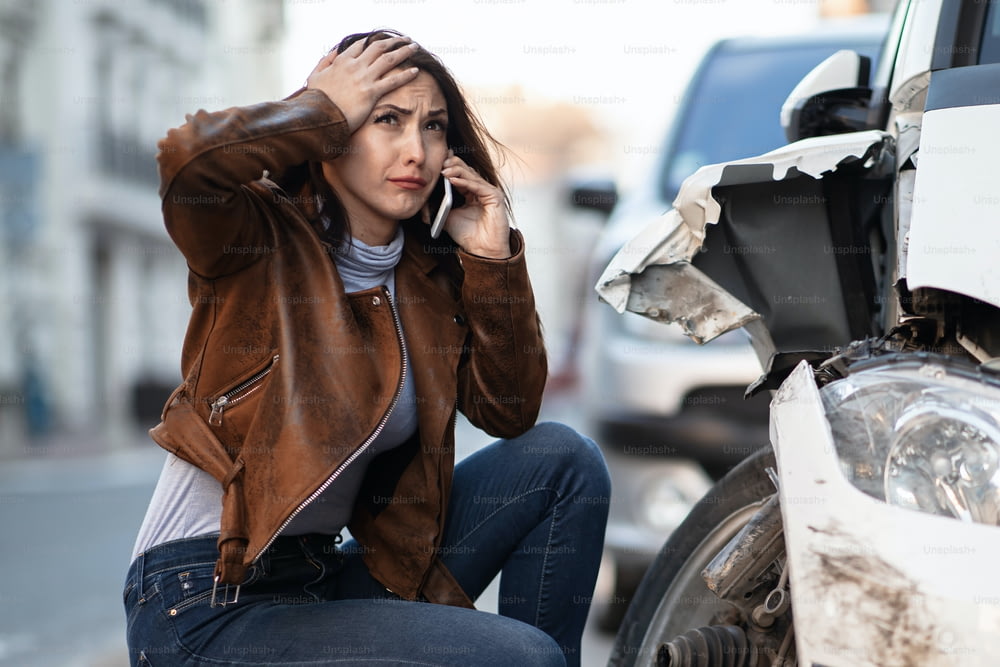 Une femme frustrée appelle l’assistance routière après l’accident de voiture.