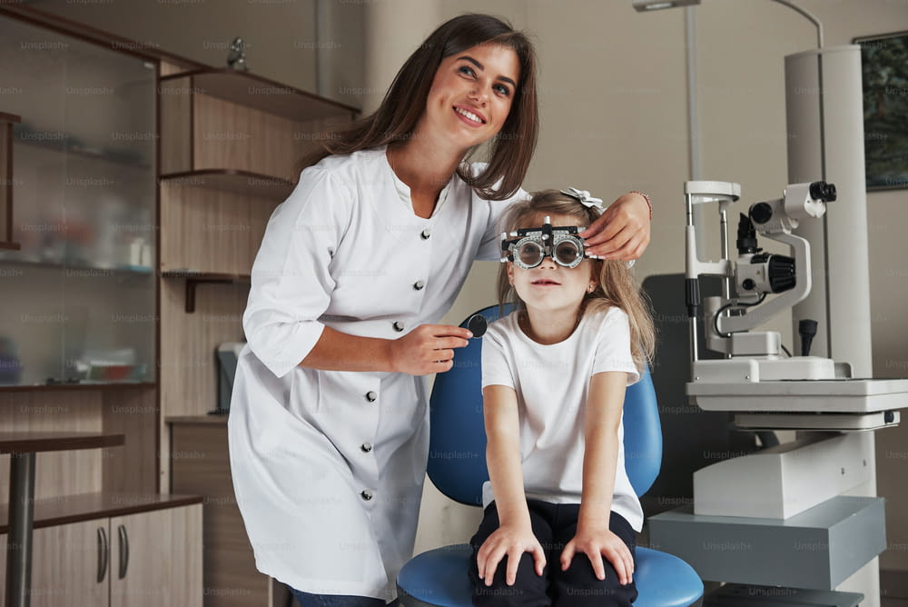 Dispositivo medico sullo sfondo. Bambina con gli occhiali seduta in clinica e che si fa testare gli occhi.