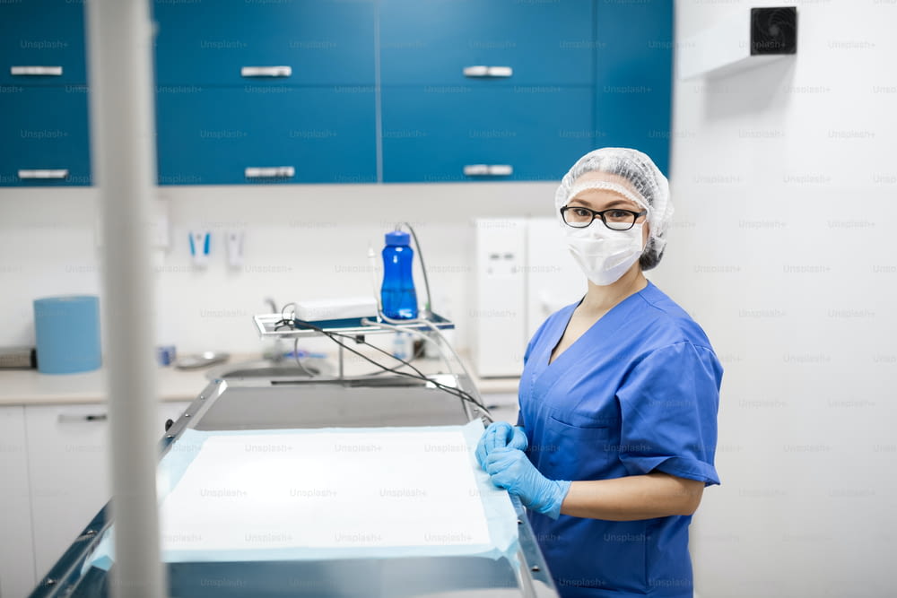 Veterinário de máscara. Veterinária profissional vestindo uniforme azul e máscara se preparando para a cirurgia