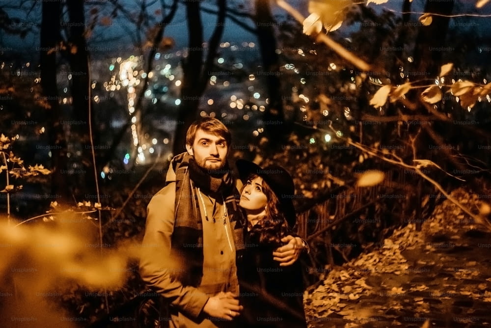 couple élégant heureux étreignant et se tenant la main avec tendre sous la lanterne jaune dans les lumières nocturnes de la ville