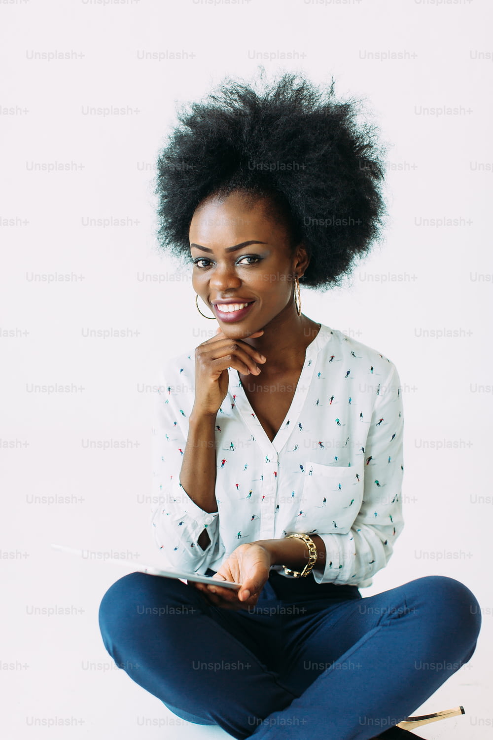 Jovem empresária afro-americana usando o tablet enquanto está sentada no chão, isolada no branco.