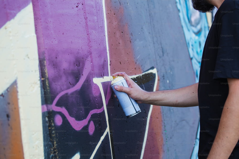거리 예술가 그림 화려한 낙서 일반 벽 - 도시 남자가 공연하고 멀티 컬러 에어로졸 스프레이로 라이브 벽화를 준비하는 현대 미술 개념