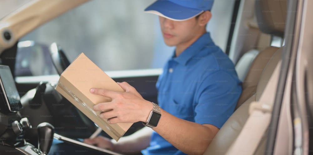 Young startup man checking orders for customers while sitting in the car preparing orders for shipping