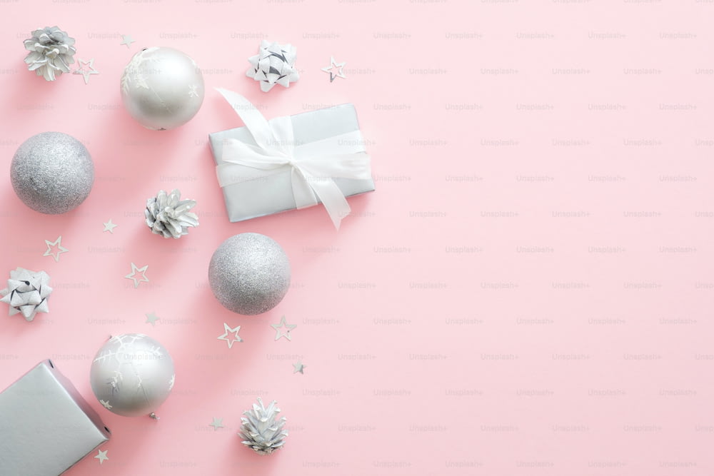 Décorations de Noël en argent, boules, boîte-cadeau, pommes de pin sur fond rose pastel. Composition minimale de Noël avec un décor de luxe moderne. Mise à plat, vue de dessus, espace de copie