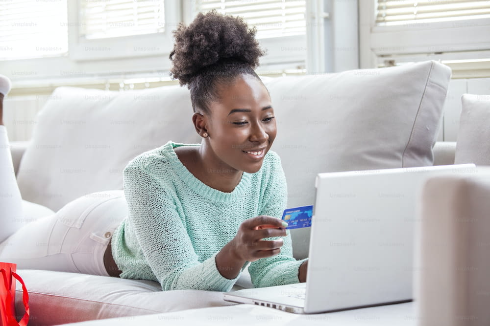 Picture showing pretty woman shopping online with credit card. African American woman holding credit card and using laptop. Online shopping concept