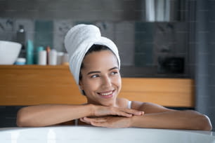 Closeup portrait of a smiling beautiful young lady leaning on the edge of the bathtub