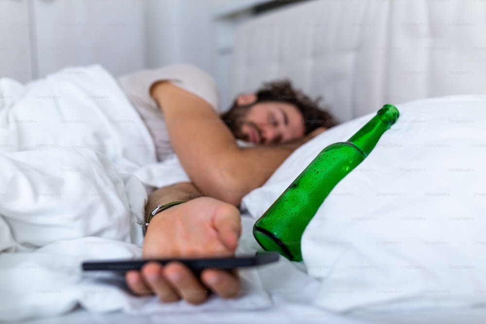 술에 취한 개념으로 문자 메시지. 침대에 누워 있는 젊은 남자는 빈 술병을 들고 술에 취해 죽는다. 술에 취한 . 알코올 중독 습관성 술 취함 유해한 습관 개념