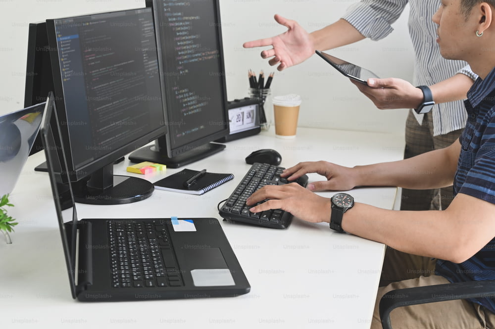 Programmeur de plans recadrés consultant avec tablette et ordinateur sur l’espace de travail du développeur.