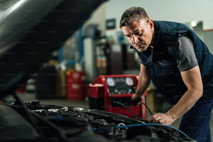Auto mechanic maintaining air conditioning system of a car at repair workshop.