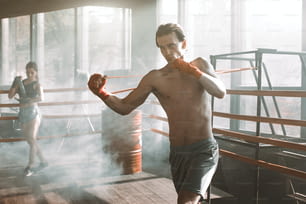 Hübscher Mann, der mit Widerstandsband im Boxring im Fitnessstudio trainiert.. Perfekt geformte Arm- und Rückenmuskulatur.