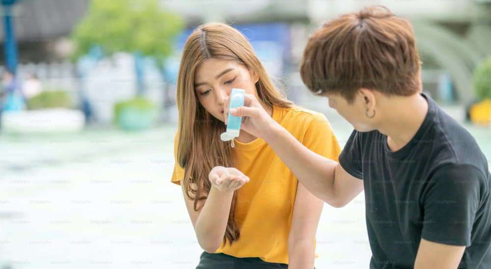 手と指を洗うアルコールジェルを使用する若いアジアの男性と女性