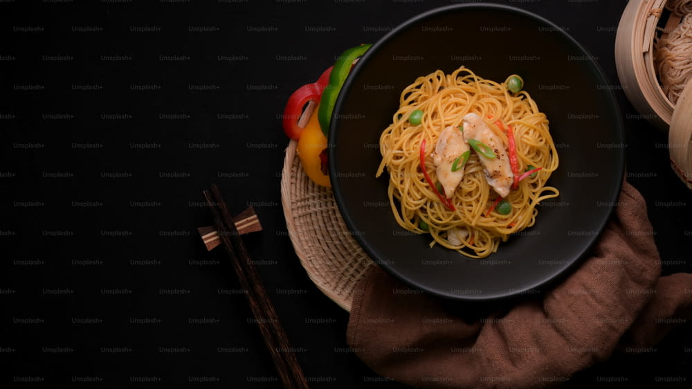 Overhead shot of Schezwan Noodles or Chow Mein with vegetable, chicken and chilli sauce served in black bowl