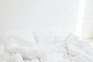 아침에 아늑한 흰색 침대. 현대적인 화이트 룸의 침대에 화이트 시트와 베개. 게으른 날. 집에 계세요. 편안한 장소. 주말에는 호텔 객실에서 휴식을 취하십시오. 지저분한 침대