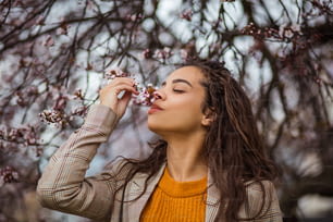 Profumo di natura. Donna afroamericana nel parco che sente l'odore del fiore.