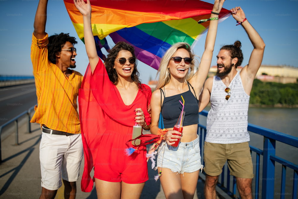 Grupo feliz de pessoas, amigos saindo na cidade acenando LGBT com bandeira do orgulho