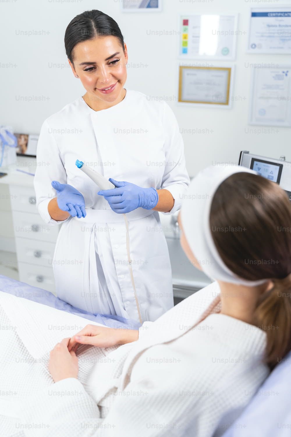 Woman in white bathrobe listening to her cosmetologists explanations before a cosmetic procedure