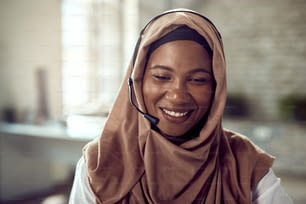 Happy Islamic businesswoman wearing a headset while working in the office.