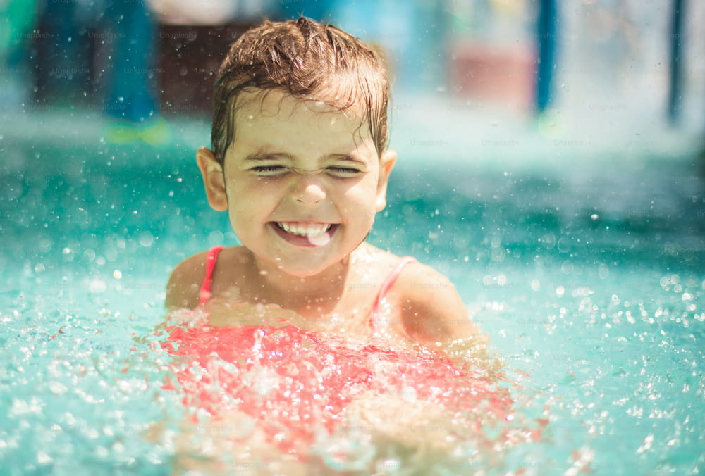 Giorno d'estate. Bambina sorridente che gioca in piscina.