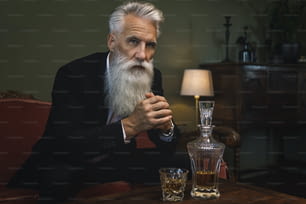 Homem idoso barbudo elegante e bonito bebendo uísque