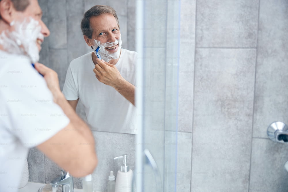 Portrait of a man with a safety razor in his hand staring in the mirror