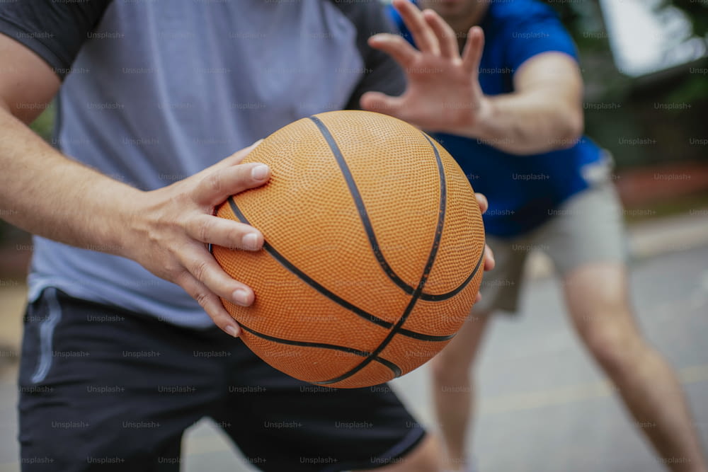 Close up of hands holding ball. Friends playing basketball in the park.