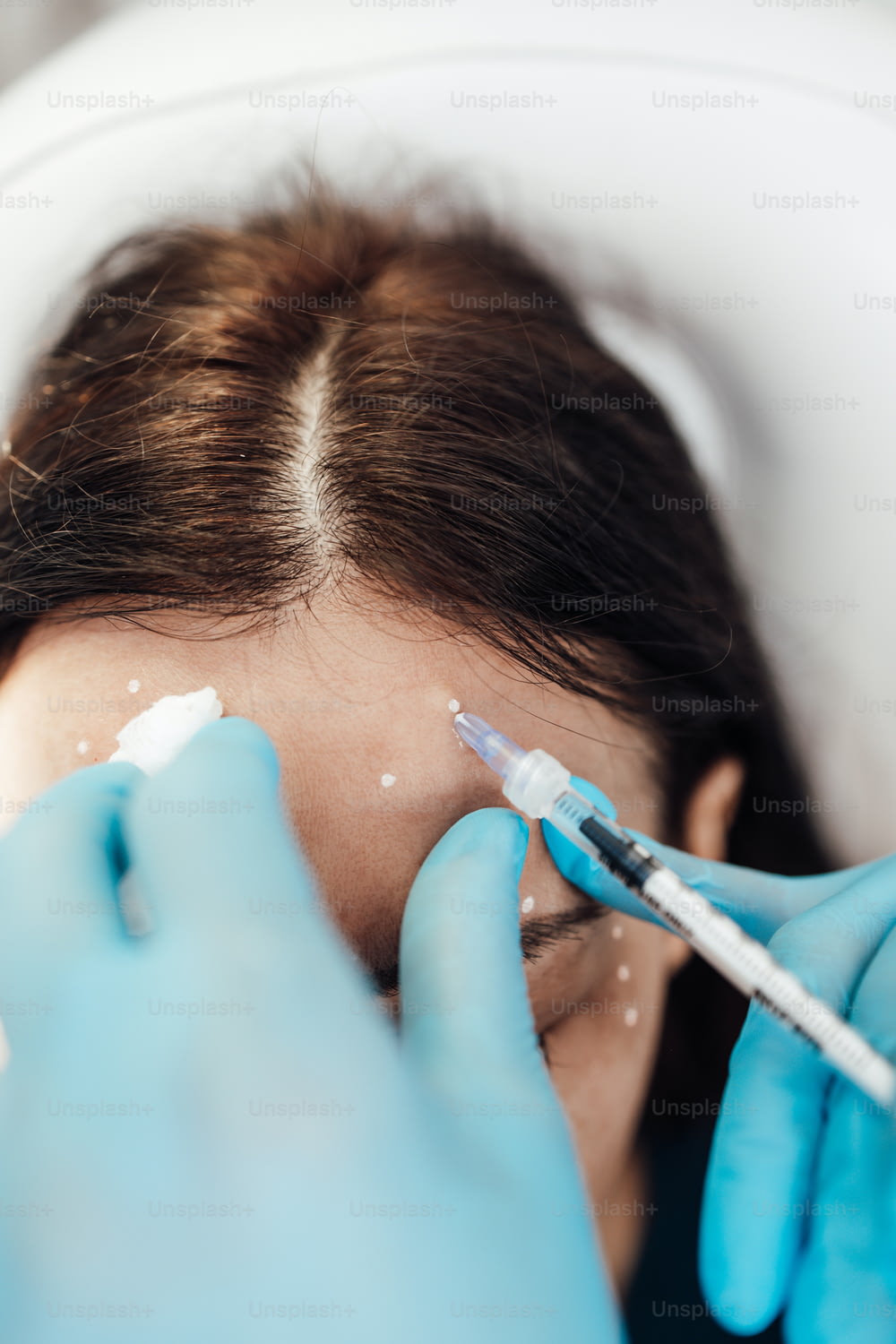 Una atractiva mujer rubia está recibiendo inyecciones faciales rejuvenecedoras en una clínica de belleza. La experta esteticista está rellenando las arrugas femeninas con botulinum.