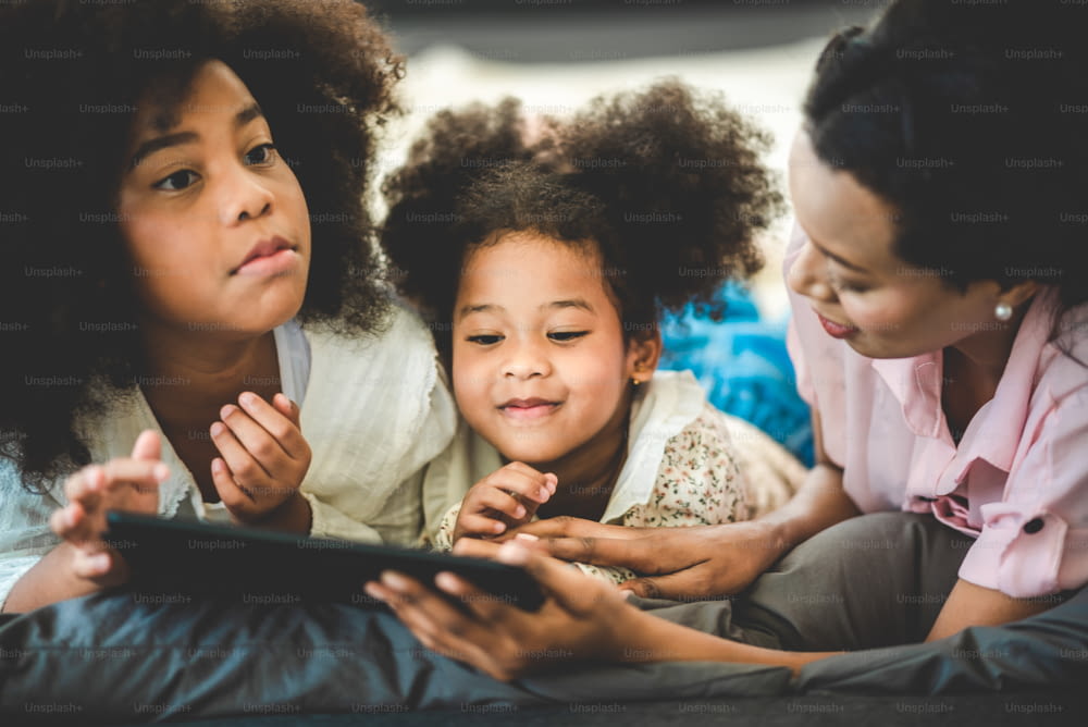 Glückliche amerikanische afrikanische Familie beobachtet Tablet auf dem Bett zu Hause, Das Konzept von Familien jeden Alters genießt die Aktivitäten im Haus.