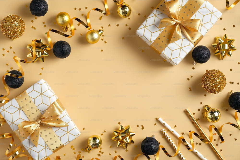 Christmas or New Year frame composition. Christmas decorations in gold and black colors and gift boxes on golden background with copy space for text. Flat lay, top view.