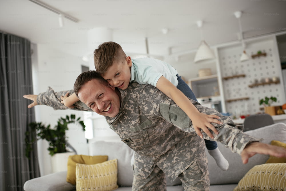 Happy soldier play with his son. Soldier enjoying at home with children.