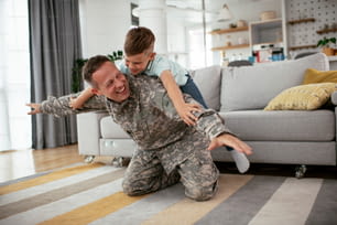 Happy soldier play with his son. Soldier enjoying at home with children.