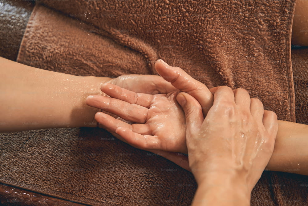 마사지 치료사가 마사지를 하는 동안 수건에 여성 손의 초상화를 닫습니다.