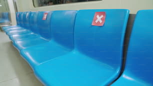 Posto a sedere in pubblico nella metropolitana sotterranea pubblica con cartelli di distanziamento sociale per mantenere la distanza di un posto a sedere per proteggere la diffusione di COVID-19 o Coronavirus .