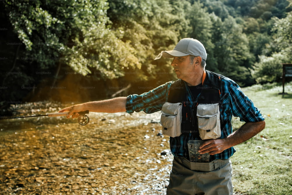 Un homme âgé pêche seul sur une rivière de montagne rapide. Concept de pêche à la mouche active et sportive.