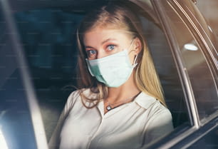 신규 표준. 마스크를 쓴 차 뒤에 앉아 있는 십대. 마스크로 보호되는 택시에 탄 젊은 여성. 도로 안전. 코로나 바이러스 전염병.