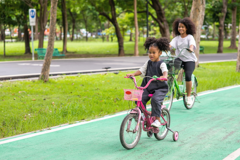 Happy two little girl enjoy and having fun riding bike together in the park.