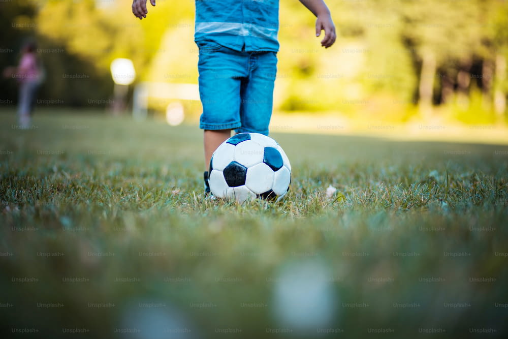 Little football player.  Legs of little boy playing football on grass. Close up.
