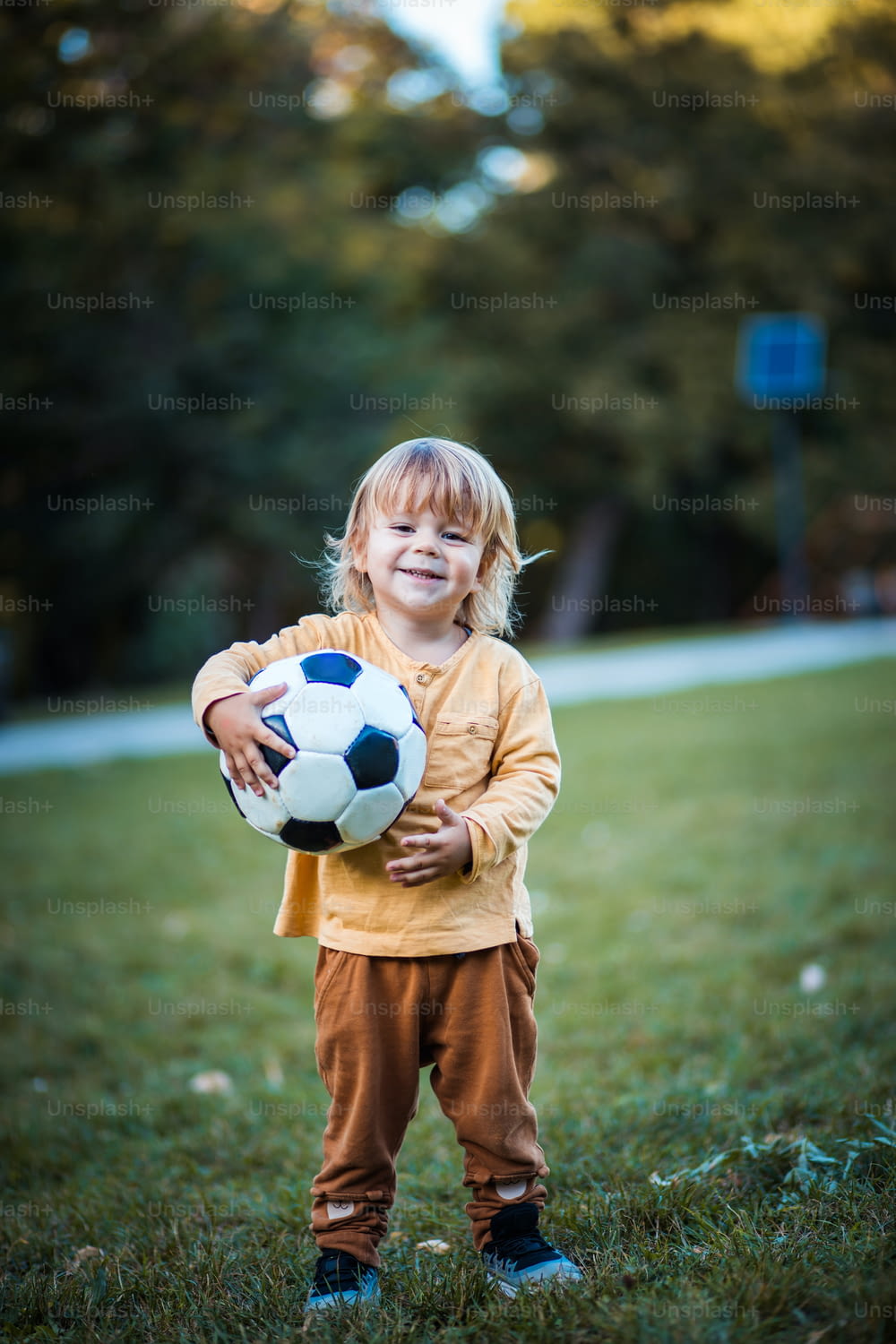 Little foot ballplayer. Little boy with football ball on grass.