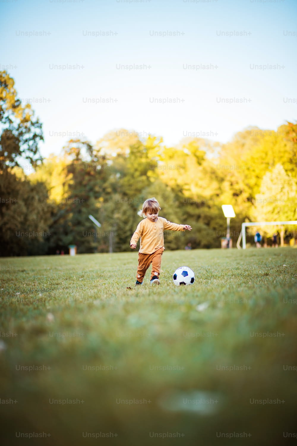 Day for football.  Little boy boy playing football alone on the grass.