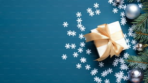 Caja de regalo de Navidad, ramas de abeto, decoración de bolas, confeti de copos de nieve sobre fondo azul oscuro con espacio de copia. Plantilla de tarjeta de felicitación de Navidad, maqueta de banner de Año Nuevo.